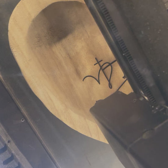 this depicts a laser engraver engraving the word faith and a cross on a prayer heart dough bowl.