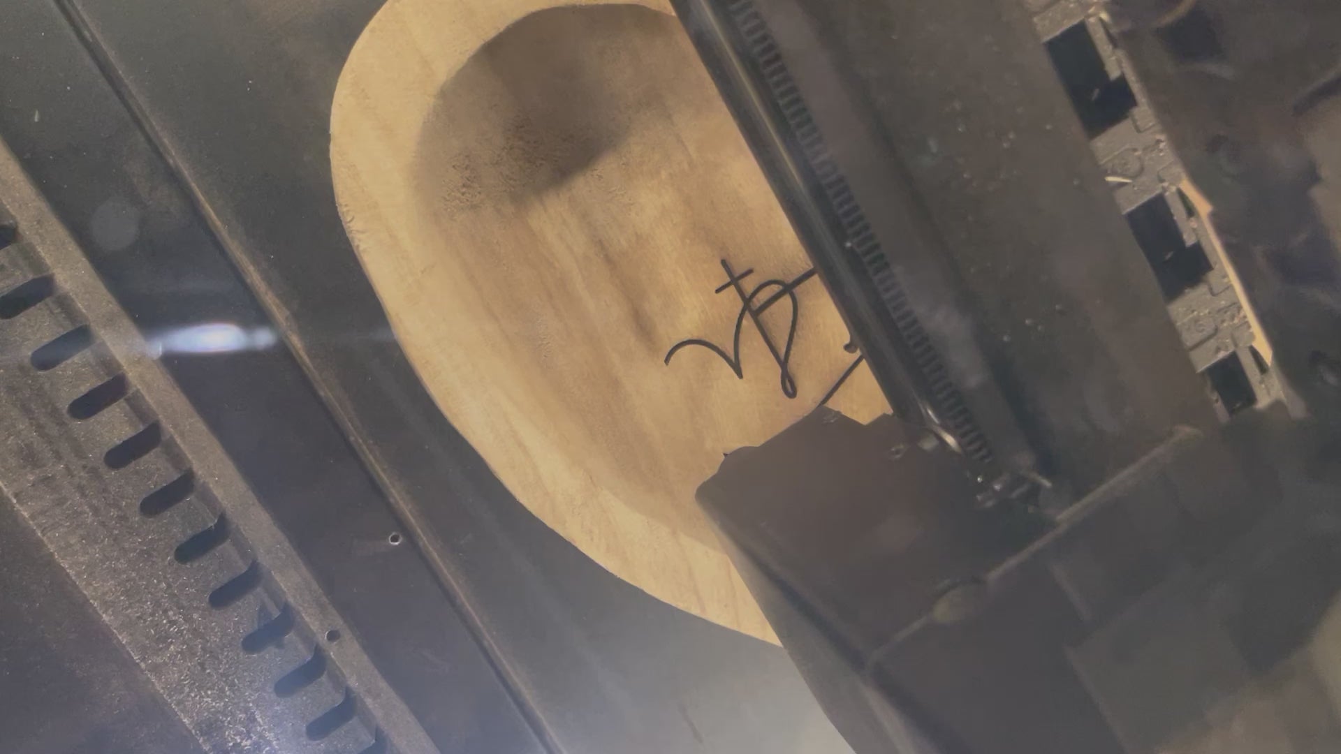 this depicts a laser engraver engraving the word faith and a cross on a prayer heart dough bowl.